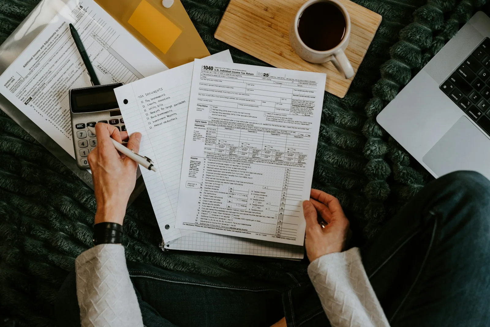 Paper financial records being organized beside a laptop